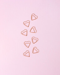 Several hearted shape clips on a pink table.