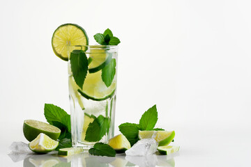 Fresh homemade mojito cocktail in a tall glass with lime, mint and ice on a white background, copy space