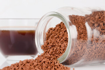 Instant coffee granules lying on the surface. Kofk granules spilled out of the jar lying on the table.