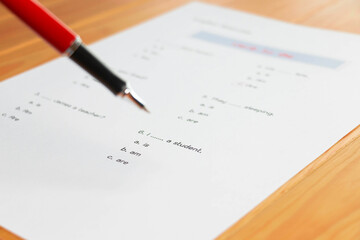 English grammar test sheet on wooden table