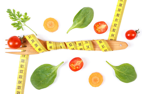 Wooden fork wrapped in tape measure and fresh ripe vegetables, concept of slimming