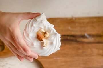 mini-pavlova with nuts. White meringue cake. A child's hand holding a dessert