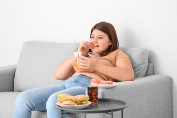 Overweight girl eating unhealthy food at home