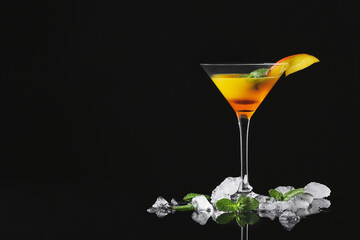 Glass of tasty mango margarita, mint and ice cubes on dark background