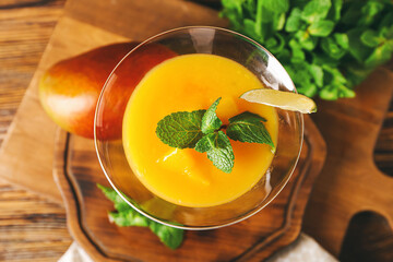 Glass of tasty mango margarita and ingredients on wooden background, closeup