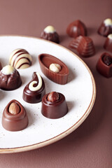 Plate with tasty chocolate candies on color background