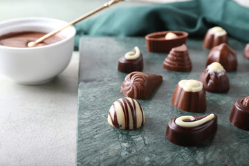 Board with tasty chocolate candies on light background