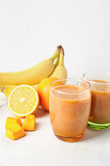 Glasses of healthy smoothie and ingredients on light color background