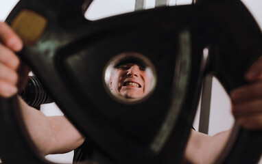 tense and full of pain the face of a man lifting a weight in a fitness club