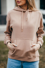 Fasion blonde woman in brown oversize hoodie, glasses and blue jeans, mockup for logo or branding...