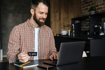 Happy mid aged brunette bearded man sitting at the table