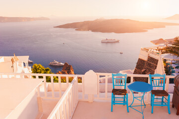 Beautiful sunset at Santorini island, Greece. Chairs with table on the terrace with sea view. Travel destinations concept