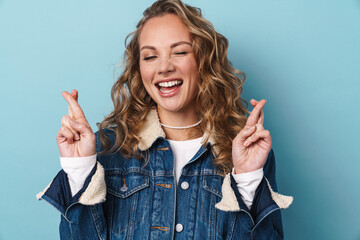 Blonde happy woman smiling and holding fingers crossed for good luck