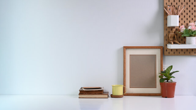 Interior Design Of Living Room With Brown Mock Up Photo Frame, Books And Houseplant On Well Arranged Desk.