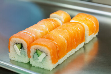 Japanese rolls with salmon on a tray on the counter. Close-up.