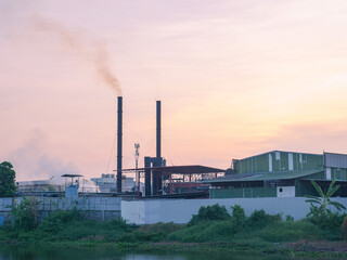 Fototapeta na wymiar outside building of industry factory with smoke and steam from smokestack near river against twilight sky the pollution of food manufacturing contaminate to environment