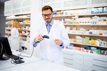 Naklejka na ściany i meble Pharmacist holding bar code reader in pharmacy store and selling medicines.