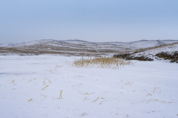 Olkhon island winter landscape. View of the mountains and frozen Lake Baikal on a cloudy day