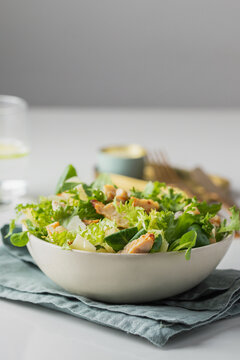 Healthy salad with  different lettuce, croutons,cheese,  chicken and dressing with especial sauce. Caesar salad in the white plate served with glass water and gold cutlery on the restaurant table.