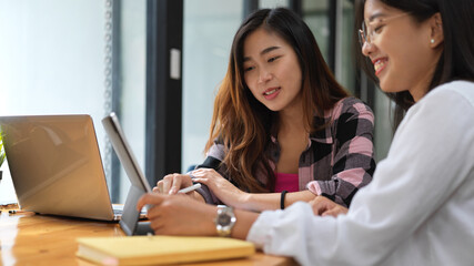 Obraz premium Two female students having funny conversation while doing group assignment