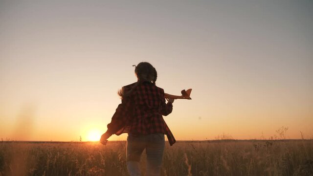 happy kid with toy airplane runs across field park, dream becoming pilot. Silhouette kid in field with airplane. Adventure journey through child lifestyle park. Happy little girl dream airplane pilot