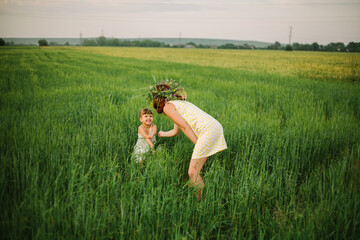 women have a wreath of wildflowers.mom and daughter playing in the field