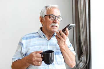 Senior man at home talking on cell phone. Cheerful man making a phone call and looking out the window Technology, communication and people concept - happy senior man calling on smartphone at home