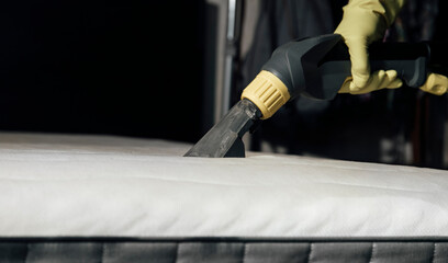 woman cleaning mattress with vacuum washing cleaner