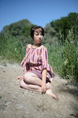 cute girl in a summer dress sitting in the sand