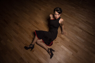 Fototapeta na wymiar Girl in tango dress sitting on a wooden floor