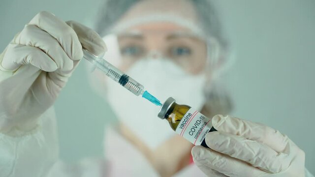 Medical doctor filling syringe from vial with anti coronavirus vaccine or medication in laboratory. Medicines research concept and defeating dangerous covid-19 infection