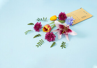 Creative concept of post delivery of the shipment full of fresh colorful flowers. Package of a bouquet of flowers on pastel blue background...