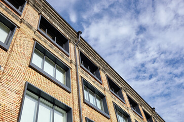 Fototapeta premium Brick building with windows and downspout against blue sky