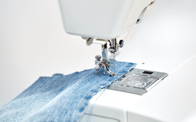 Sewing machine working part with blue denim cloth, replacement foot. A close-up shows a needle passing through tissue