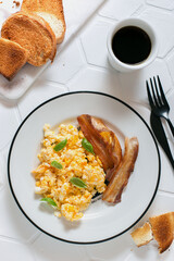 Breakfast for one person with scrambled eggs, bacon and coffee and toast, top view, selective focus
