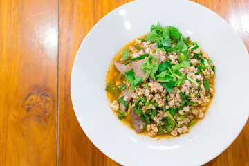 Spicy minced pork salad is traditional food of Northeast of Thailand. It contains minced pork, roasted rice, roasted chili and Thai herbs mixed together. It was put on white plate.