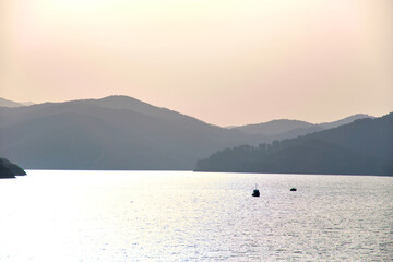 Horizontal wallpaper of a boat in the swamp with mountains in the background at sunrise. Silhouette of a boat and mountains with pastel colours