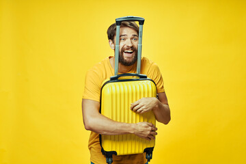 male tourist hugs yellow suitcase with hands on isolated background