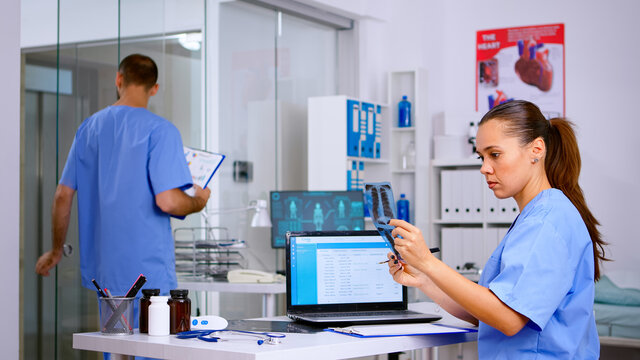 Clinician woman managing meeting schedule agenda appointment in hospital holding patient x-ray. Medical doctor nurse analysing radiography checking treatment of diagnosed patients - Powered by Adobe