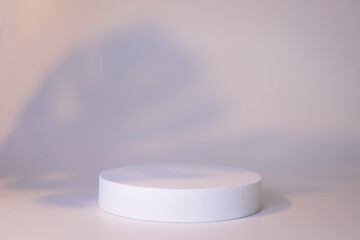 White podium on the white background with leaves shadows. Podium for product, cosmetic presentation. Creative mock up. Pedestal or platform for beauty products.