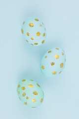 Fototapeta na wymiar Festive easter background - blue easter eggs with golden glitter dots on blue backdrop, closeup, vertical.