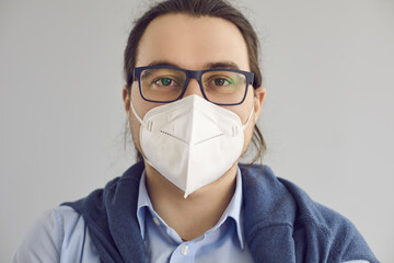 Close up headshot of happy young guy wearing eyeglasses and breathing through FPP2 KN95 N95 face...