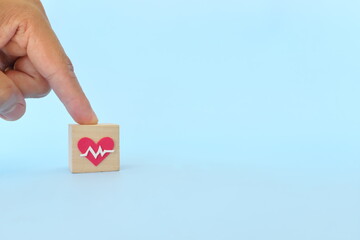 Hand choosing healthcare heartbeat icon on wooden blocks with copy space. Health top priority and medical insurance  concept.