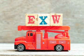 Fire ladder truck hold letter block in word EXW (abbreviation of Ex works) on wood background