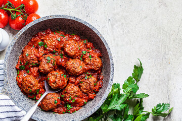 Fried meatballs with tomato sauce and parsley in  pan, top view, copy space.