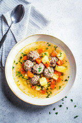 Homemade meatballs soup with vegetables, top view, gray background, Comfort food concept.