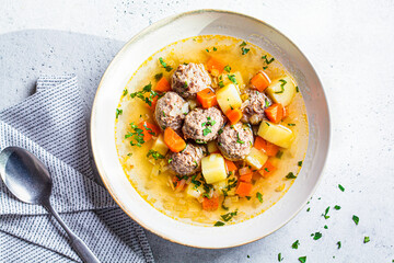 Homemade meatballs soup with vegetables, top view, gray background, Comfort food concept.