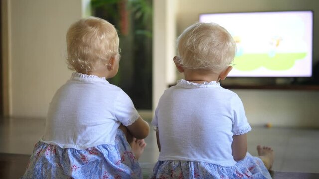 Sisters bonding time. Two little caucasian girls watching television. Back shot
