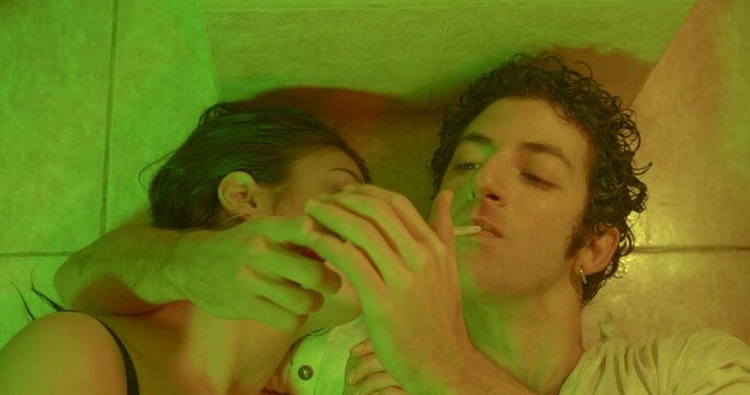 Couple smokes marijuana lying on the floor