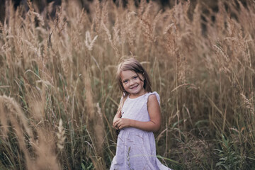 Funny cute emotional caucasian child girl among tall grass, childhood and emotions concept, happy childhood in nature